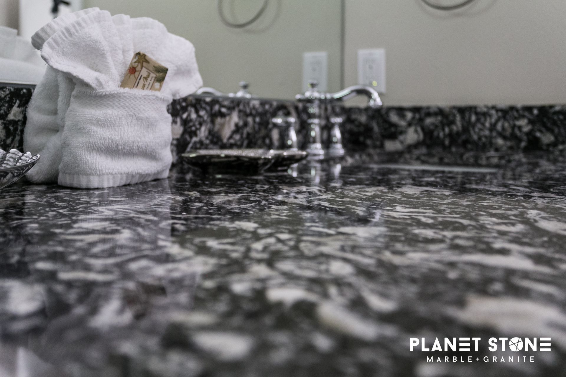 White mesh bag on speckled granite countertop beside chrome faucet in a bathroom sink.