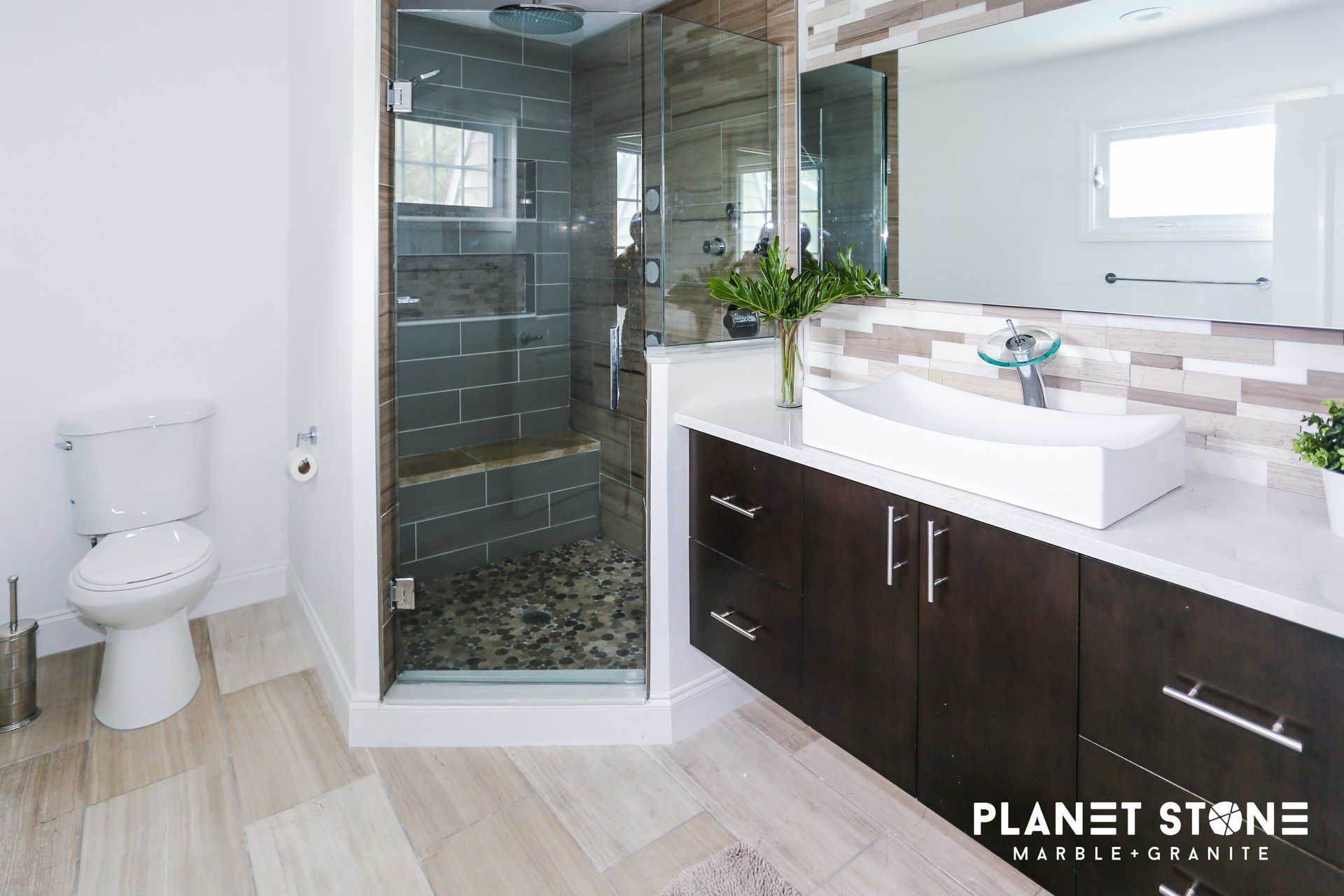 Modern bathroom with glass shower, white vanity, toilet, and light wood flooring