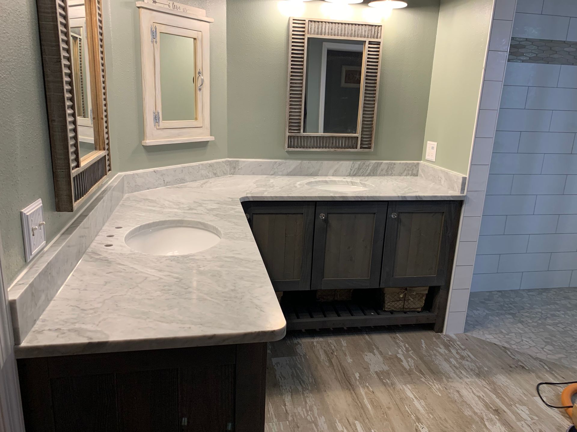 Bathroom vanity with light gray countertop, single sink, mirrors, and dark wood cabinets