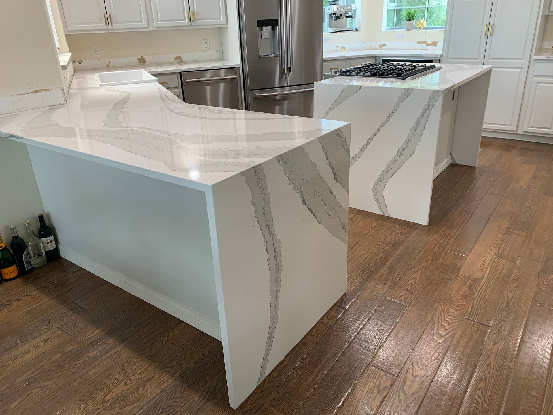 Modern white kitchen with marble island, stainless sink, and wood floors