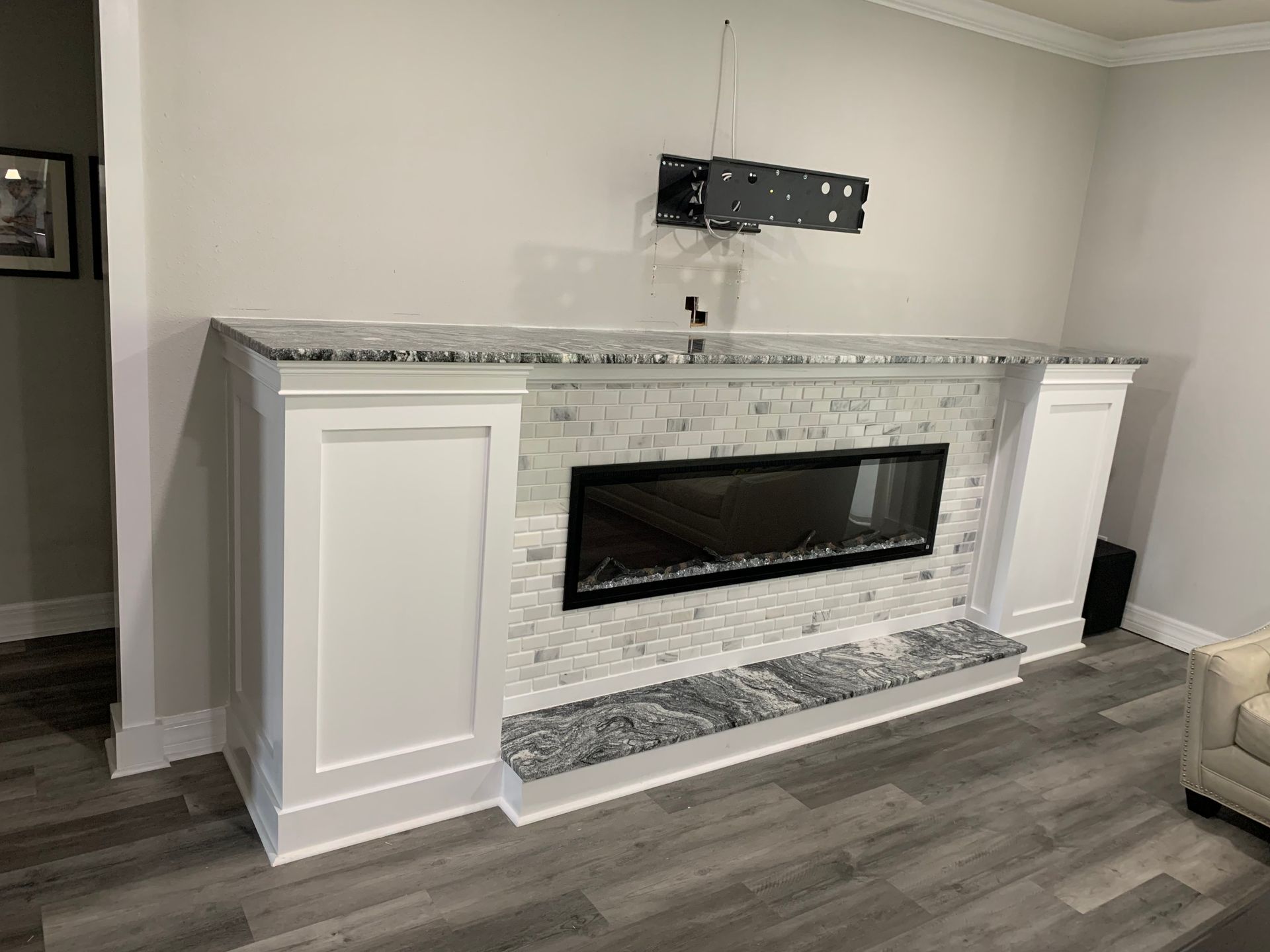 Modern living room fireplace with white cabinets, gray stone surround, and TV mount above the mantel