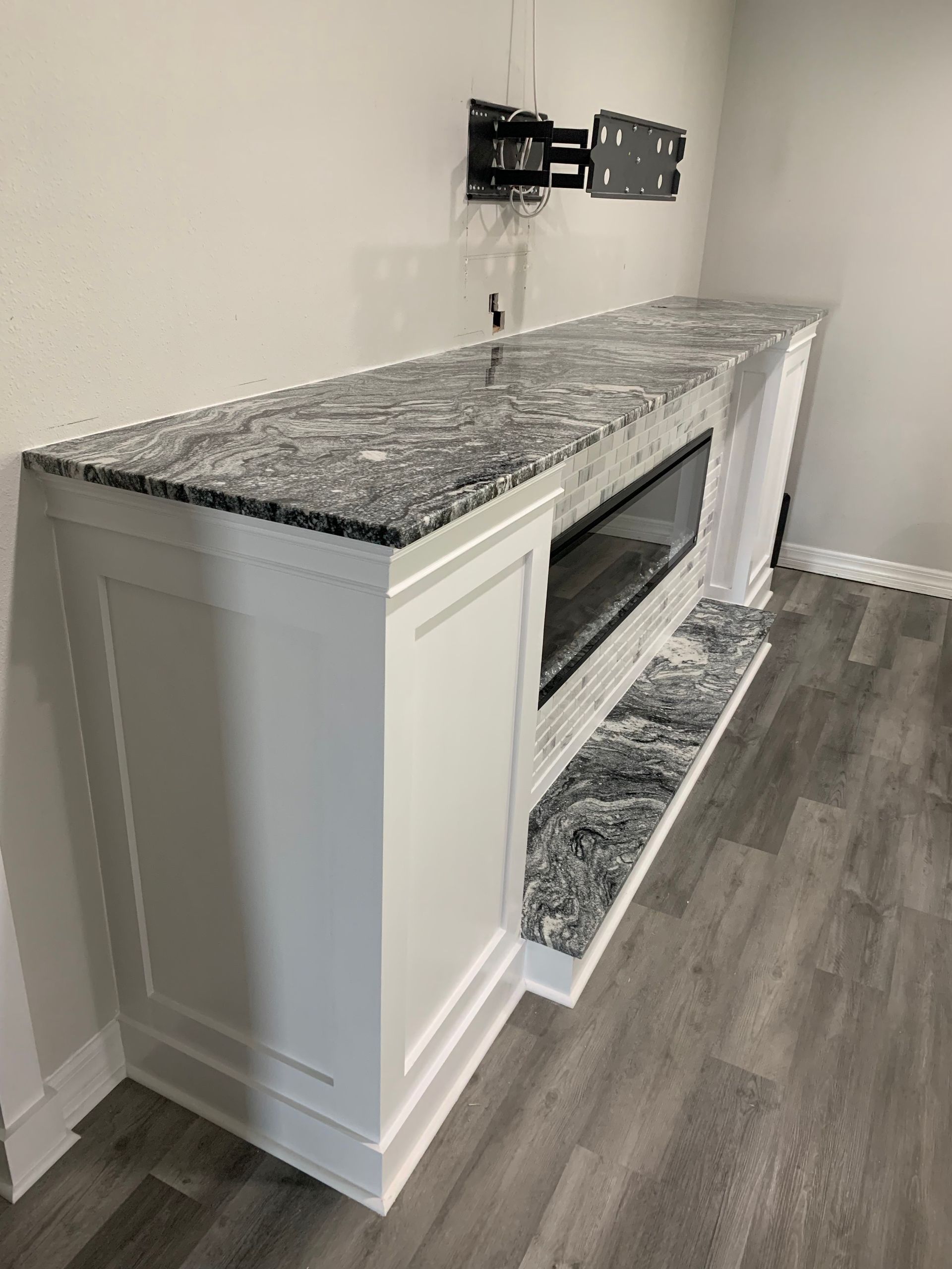 Granite-topped white fireplace mantel against a wall in a carpeted room