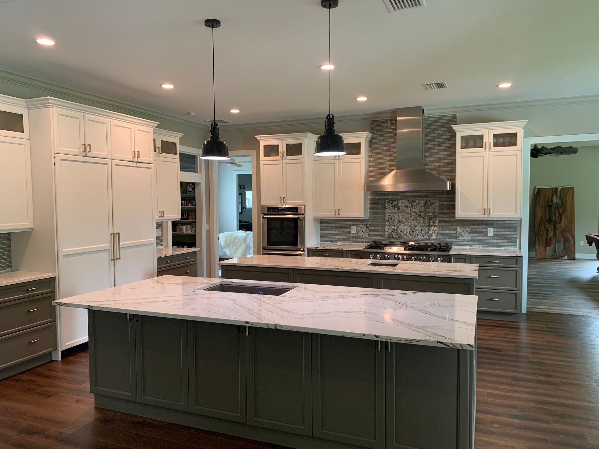 Modern kitchen with white cabinets, dark island, pendant lights, and stainless steel appliances