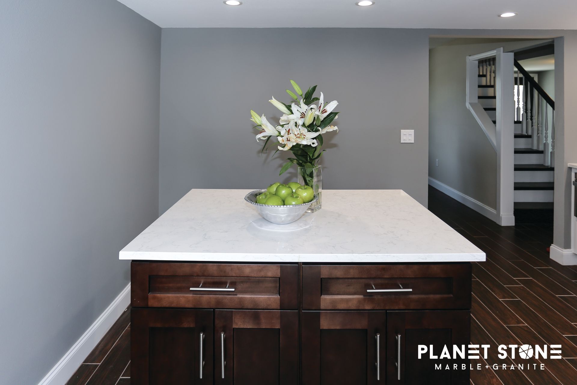 Modern kitchen island with white countertop, dark wood cabinets, and a vase of white flowers
