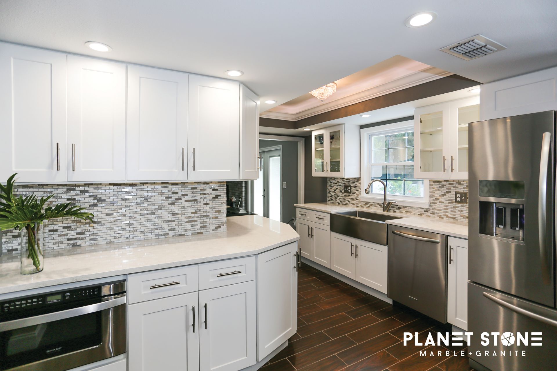 Bright modern kitchen with white cabinets, mosaic backsplash, stainless appliances, and granite countertops