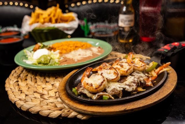 Seafood platter with grilled shrimp, rice, and a salad on a table in a dim restaurant