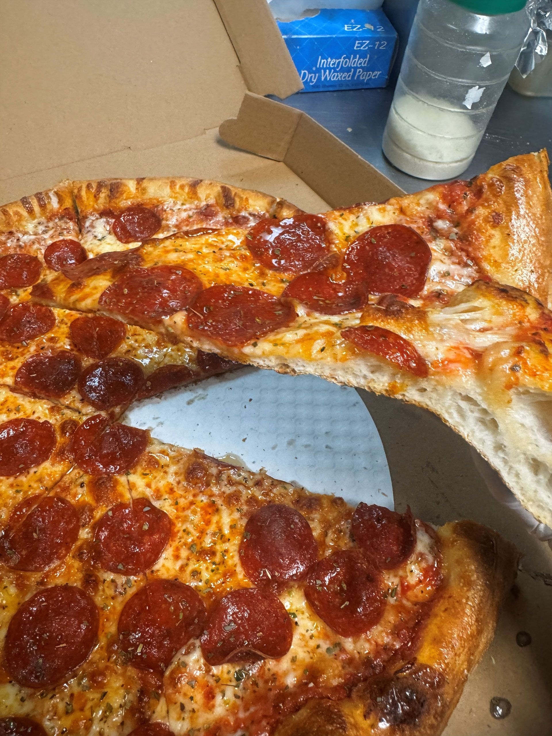 Pepperoni pizza with a slice being lifted.