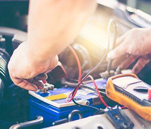 Selective focus an auto mechanic uses a multimeter voltmeter to check the voltage level in a car battery