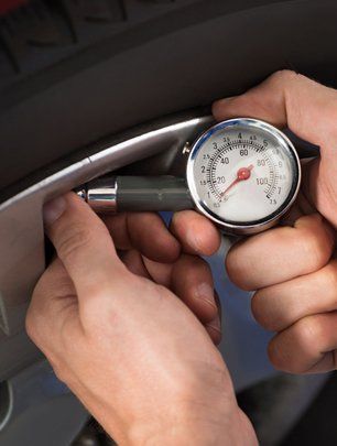 Close-up of mechanic checking air pressure level in car tire