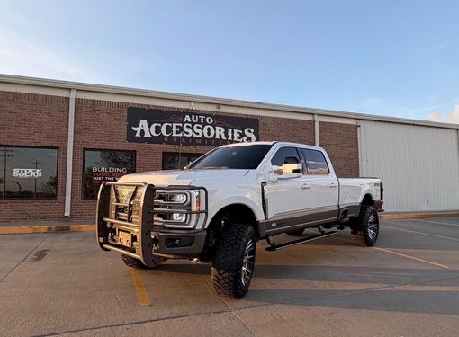Lifted silver pickup truck parked outside an auto accessories store.