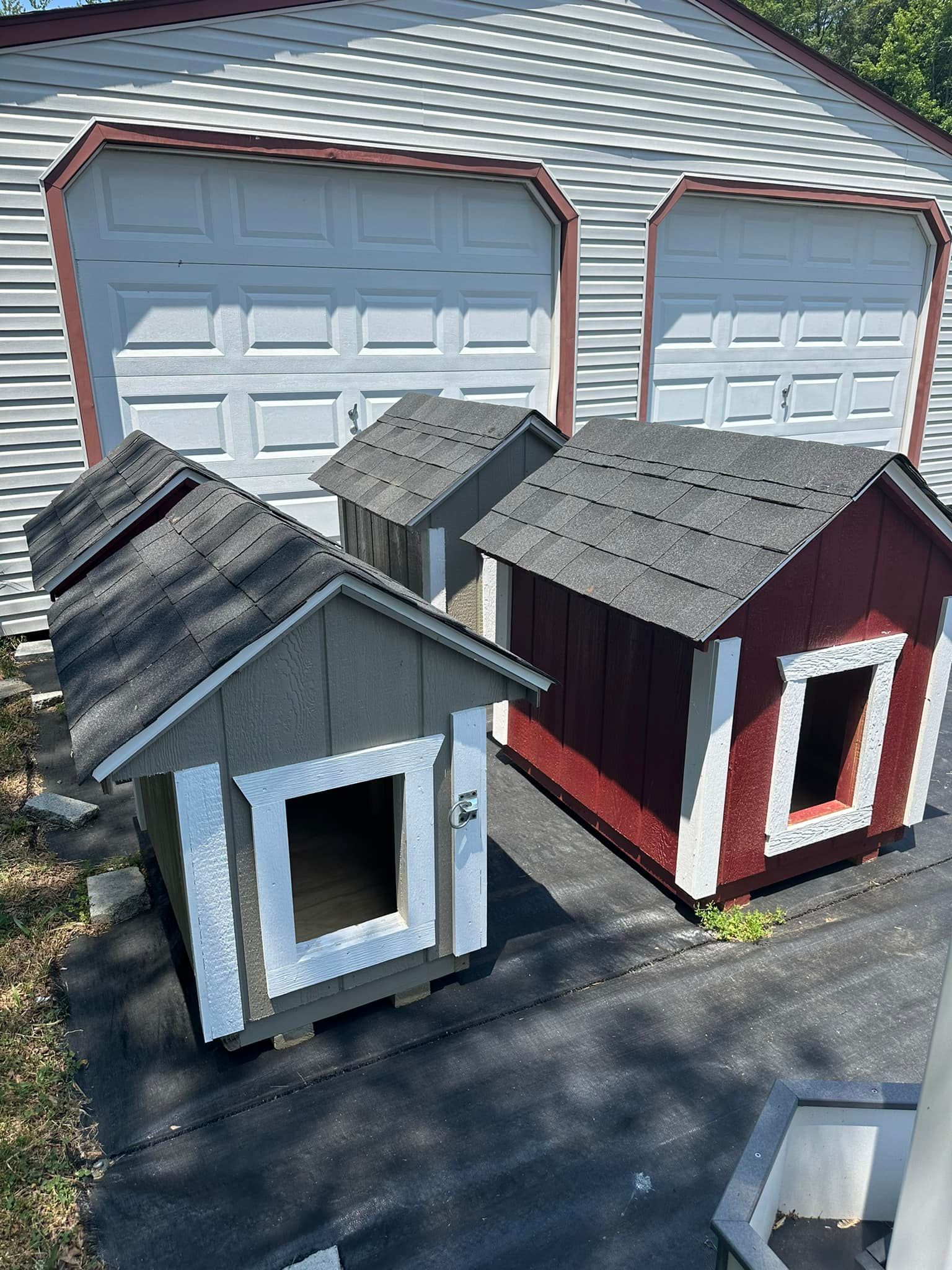 Two dog houses are sitting next to each other in front of a garage.
