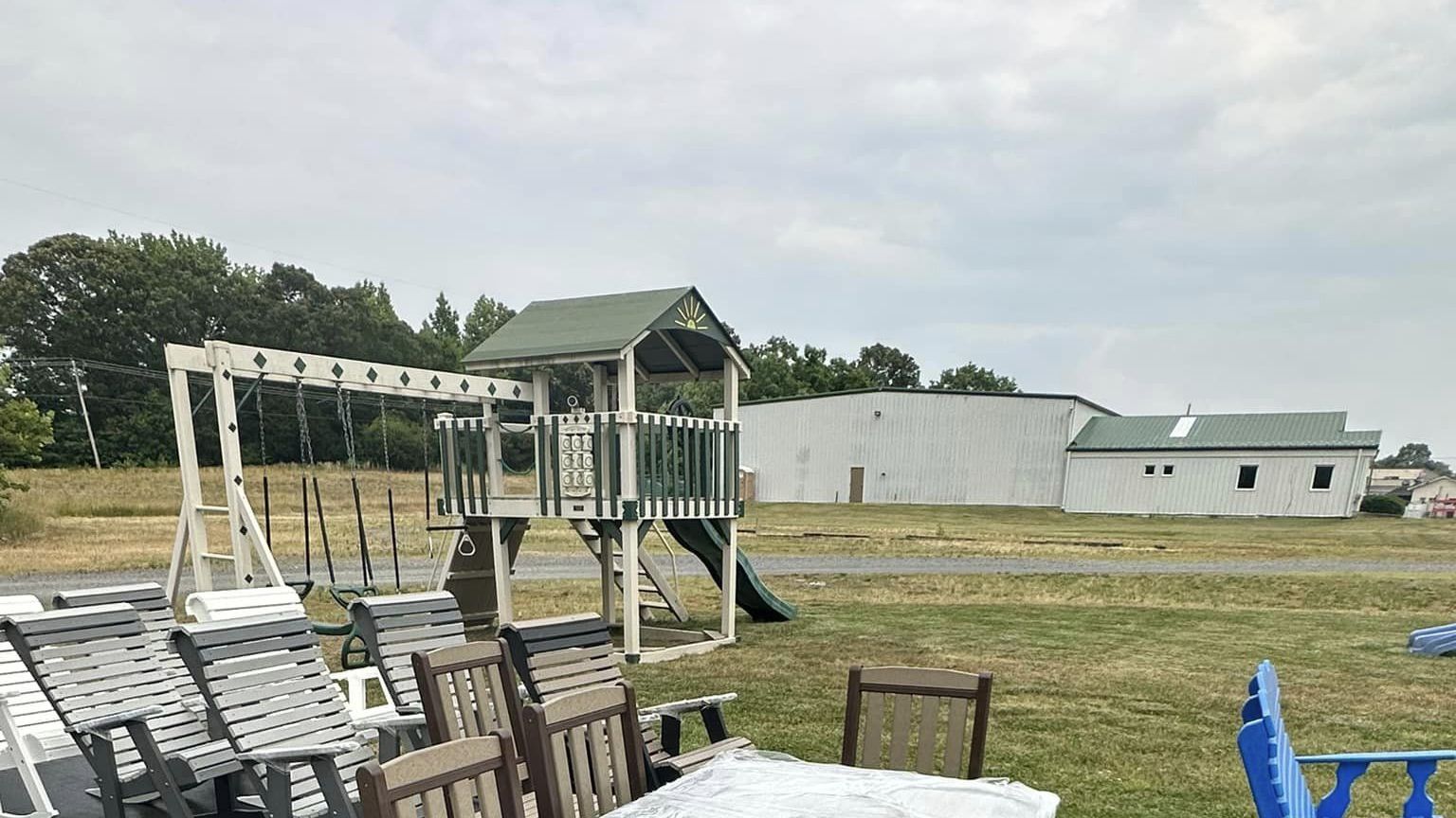 A table and chairs in a field with a playground in the background.