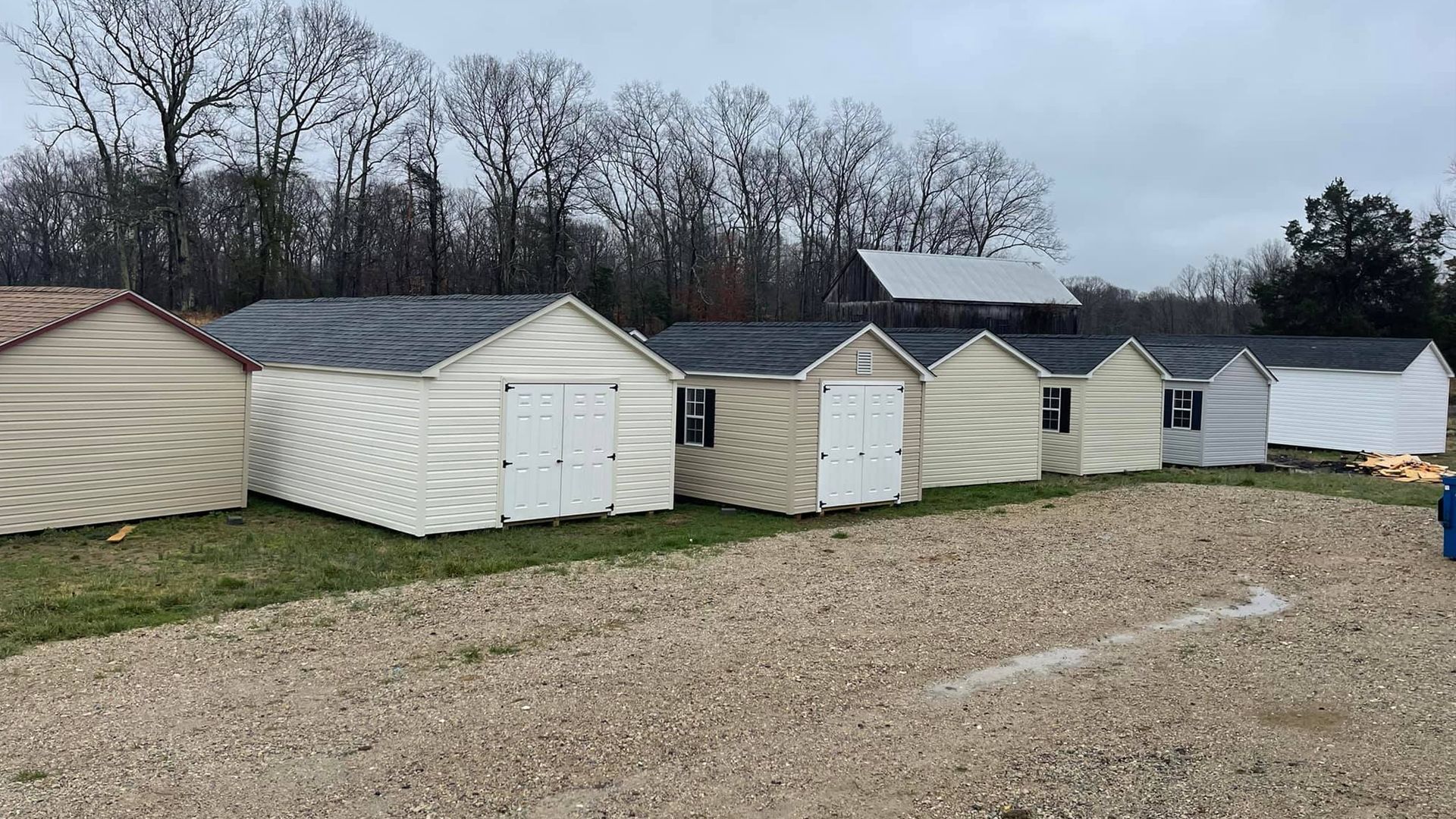 A row of sheds are lined up in a gravel lot.