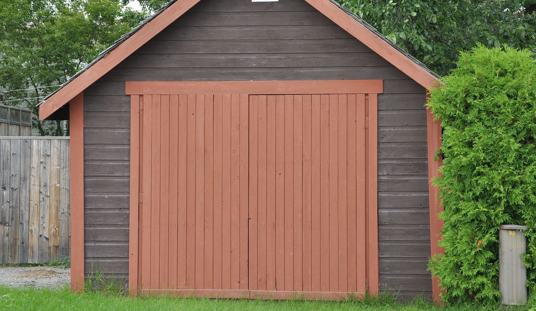 A garage with a red door and a brown roof