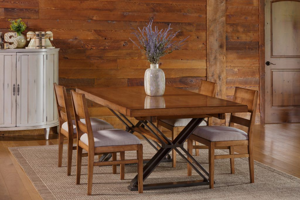 A dining room table with chairs and a vase of flowers on it.