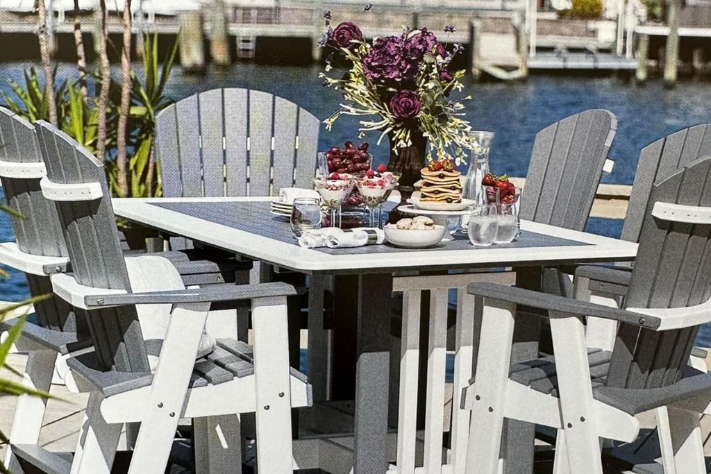 A table with a vase of flowers on it is surrounded by chairs.