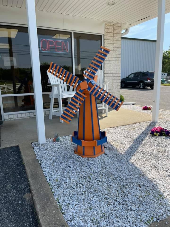 A large orange and blue windmill is sitting in front of a store.