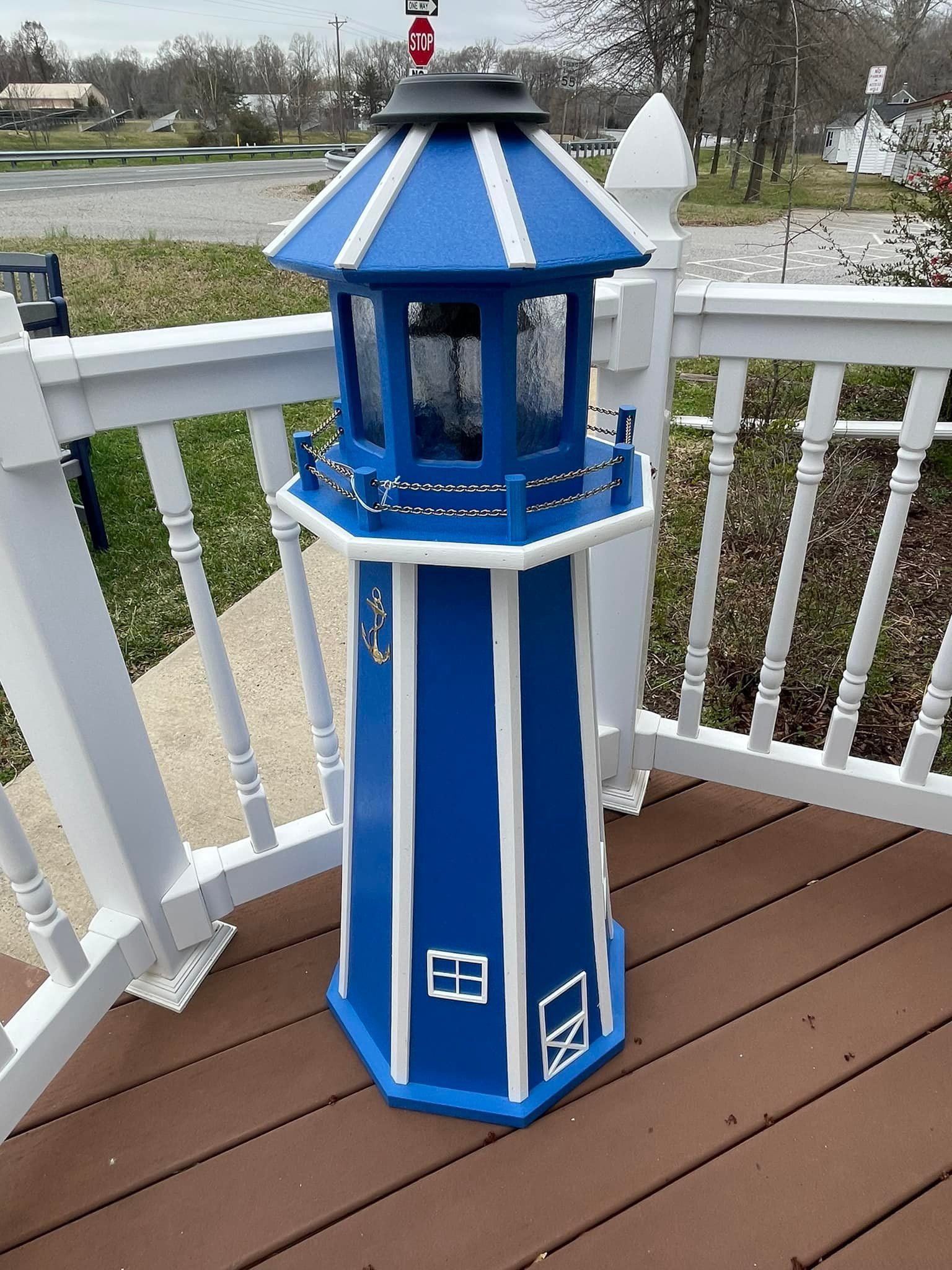 A blue and white lighthouse is sitting on a wooden deck.