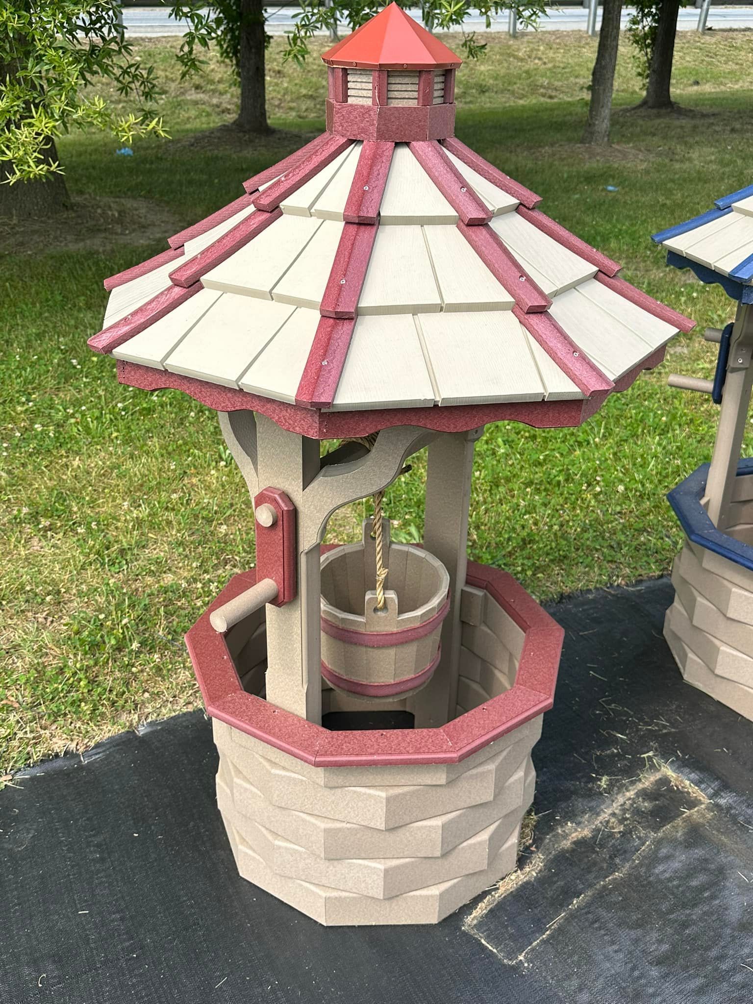 A well with a red and white roof is sitting on the ground.