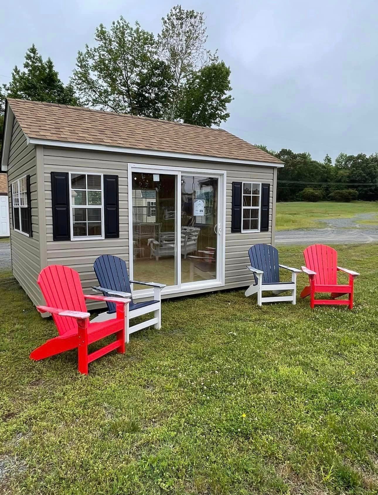 A small house with a sliding glass door and two red chairs in front of it.