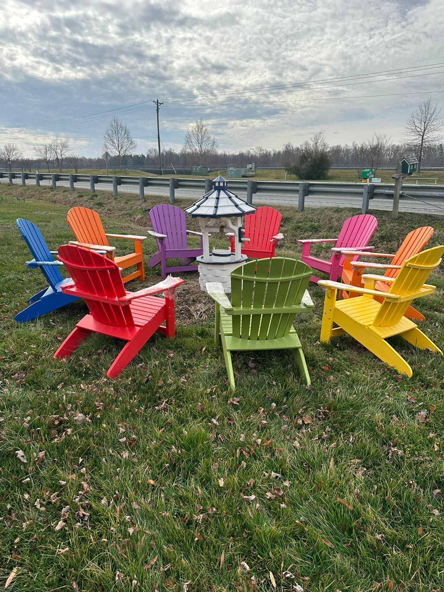 A group of colorful adirondack chairs are sitting in a grassy field.