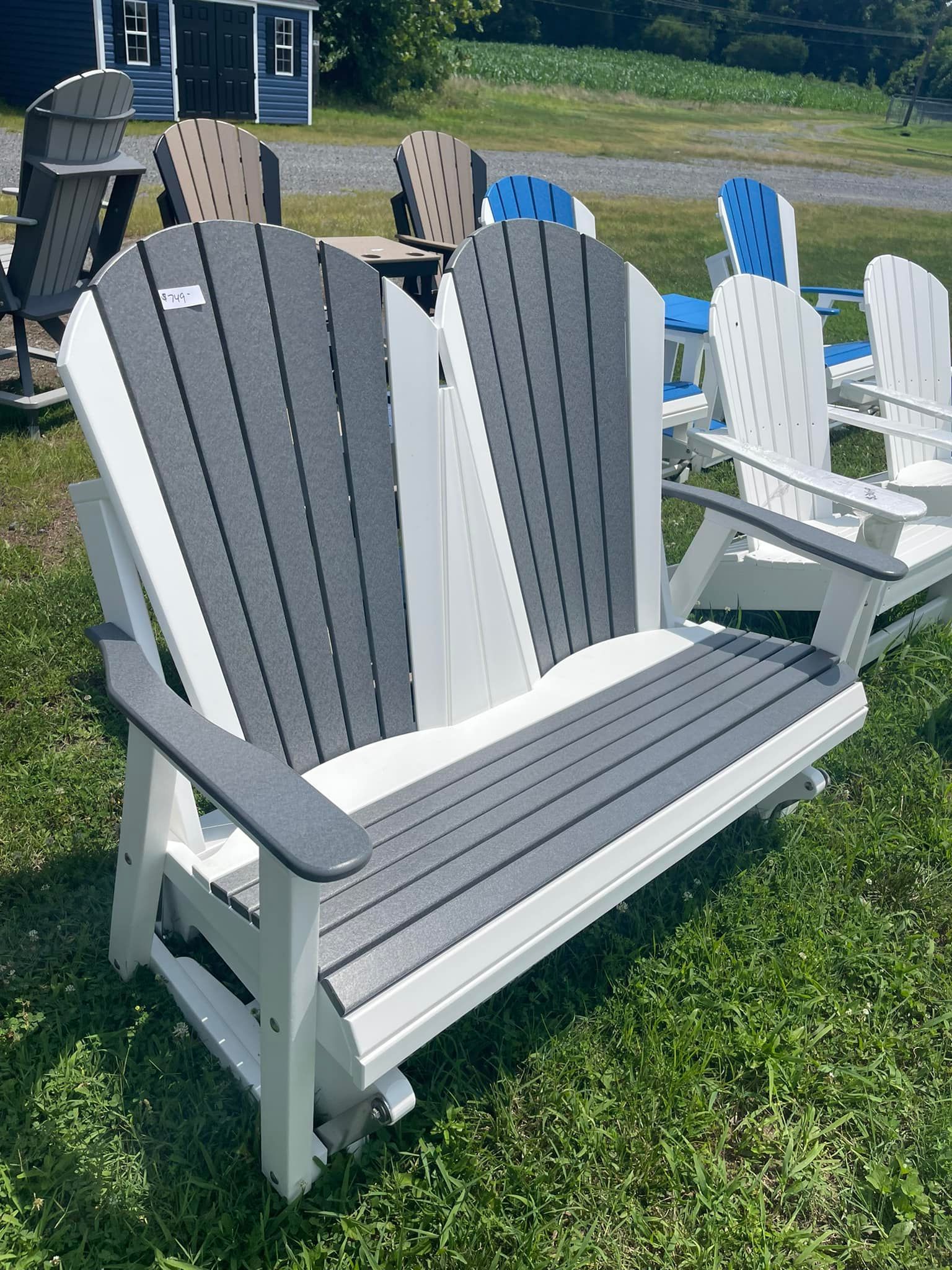 A white and gray wooden bench is sitting on top of a lush green field.