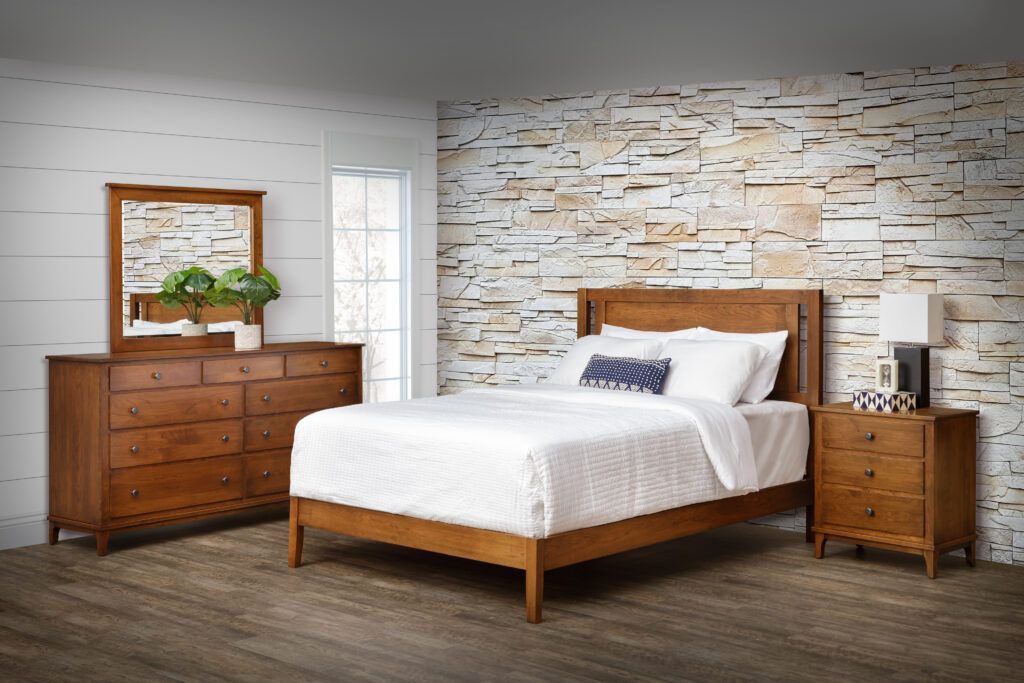 A bedroom with a bed , dresser , nightstand and mirror.