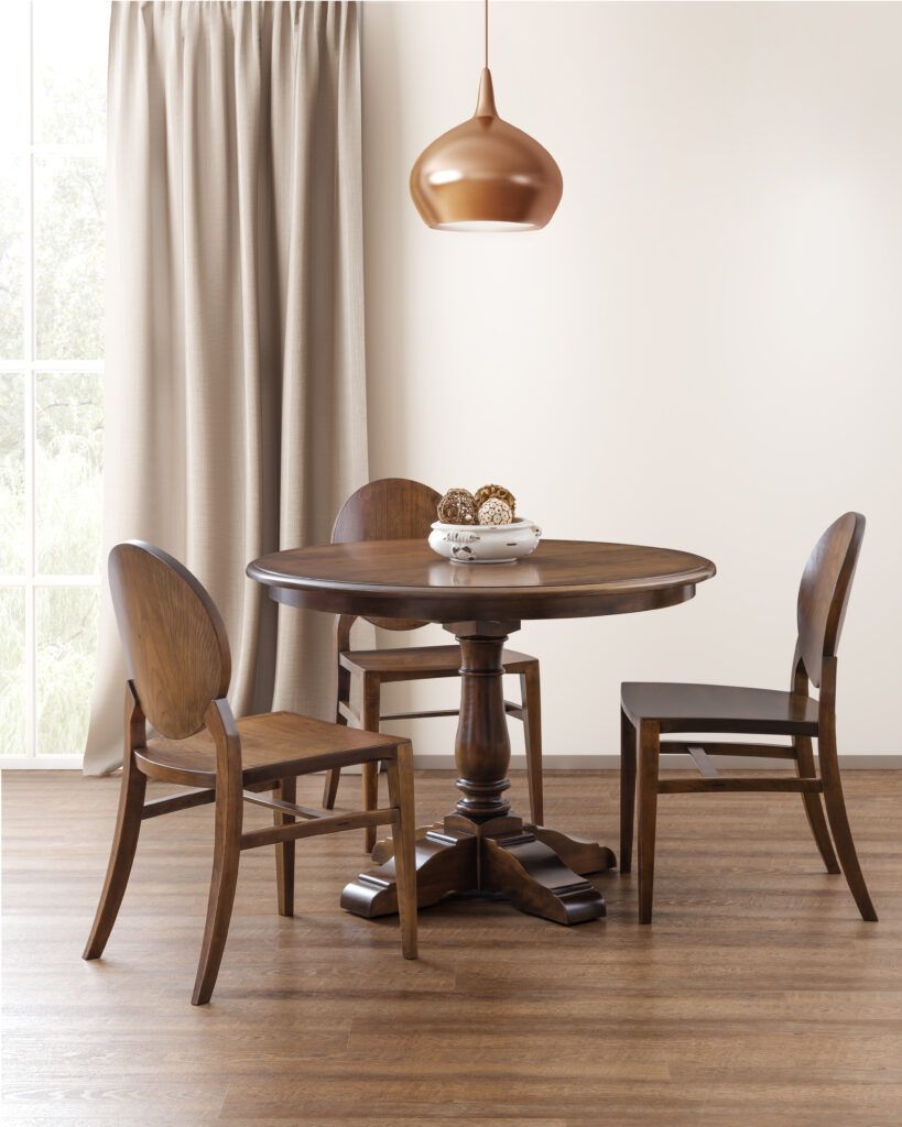 A dining room with a table and chairs in front of a window.