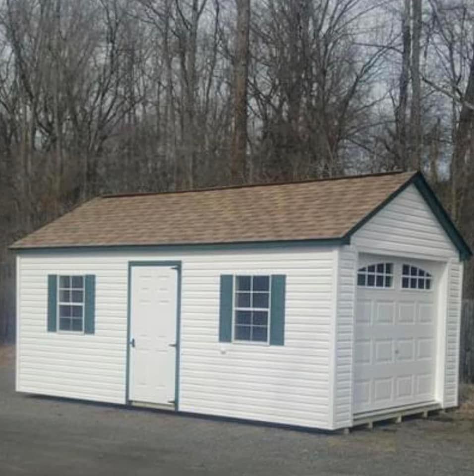 A white garage with a brown roof and green shutters