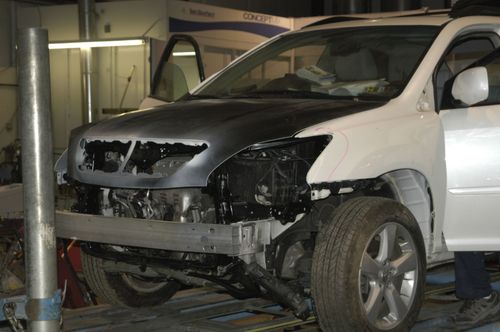 Burned black-and-white SUV with front damage in an indoor garage or repair bay