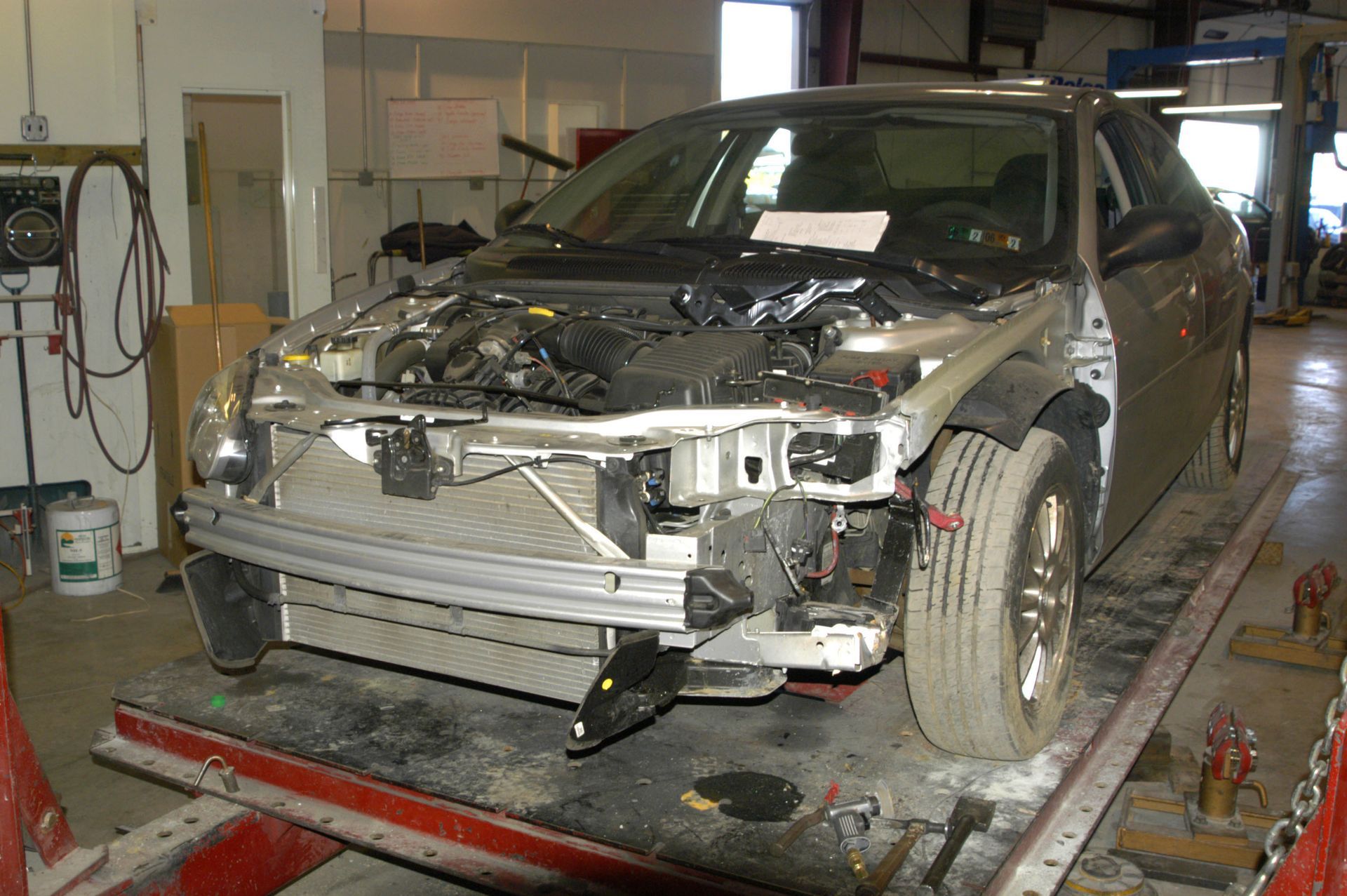 Damaged car with front end removed on a repair lift in an auto body shop