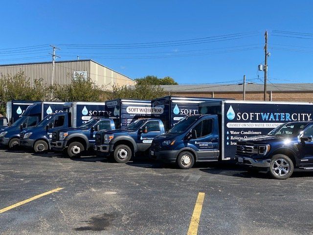 a row of soft water city trucks are parked in a parking lot .