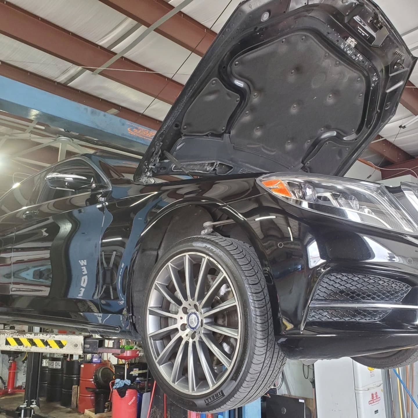 Black sports car lifted in a garage with hood open during maintenance