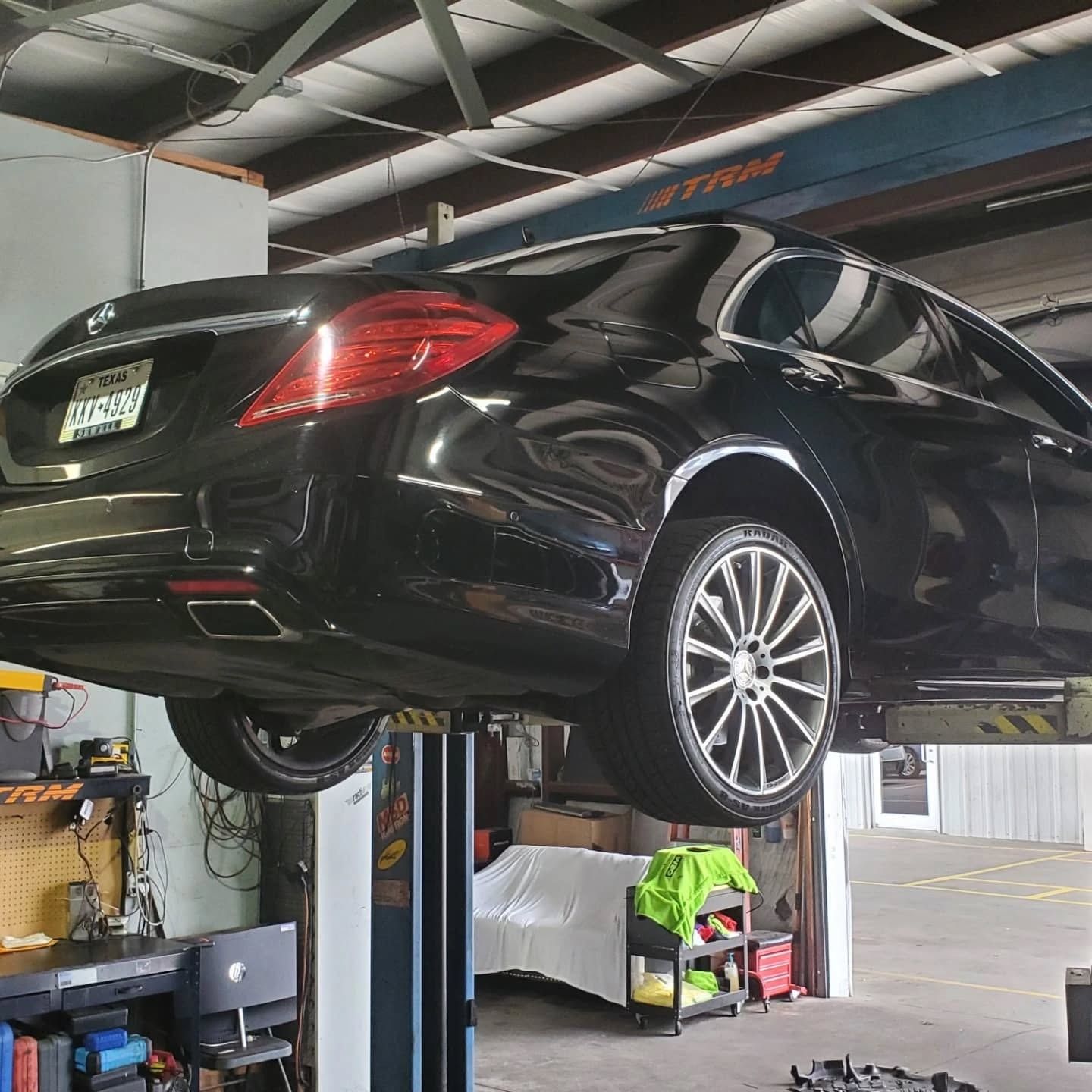 Black sedan raised on a hydraulic lift in an auto repair shop