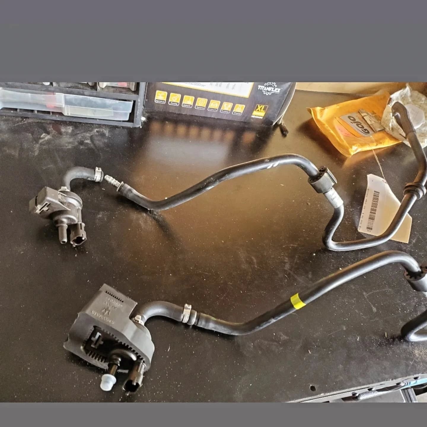 Two black automotive hoses with metal fittings laid on a workbench