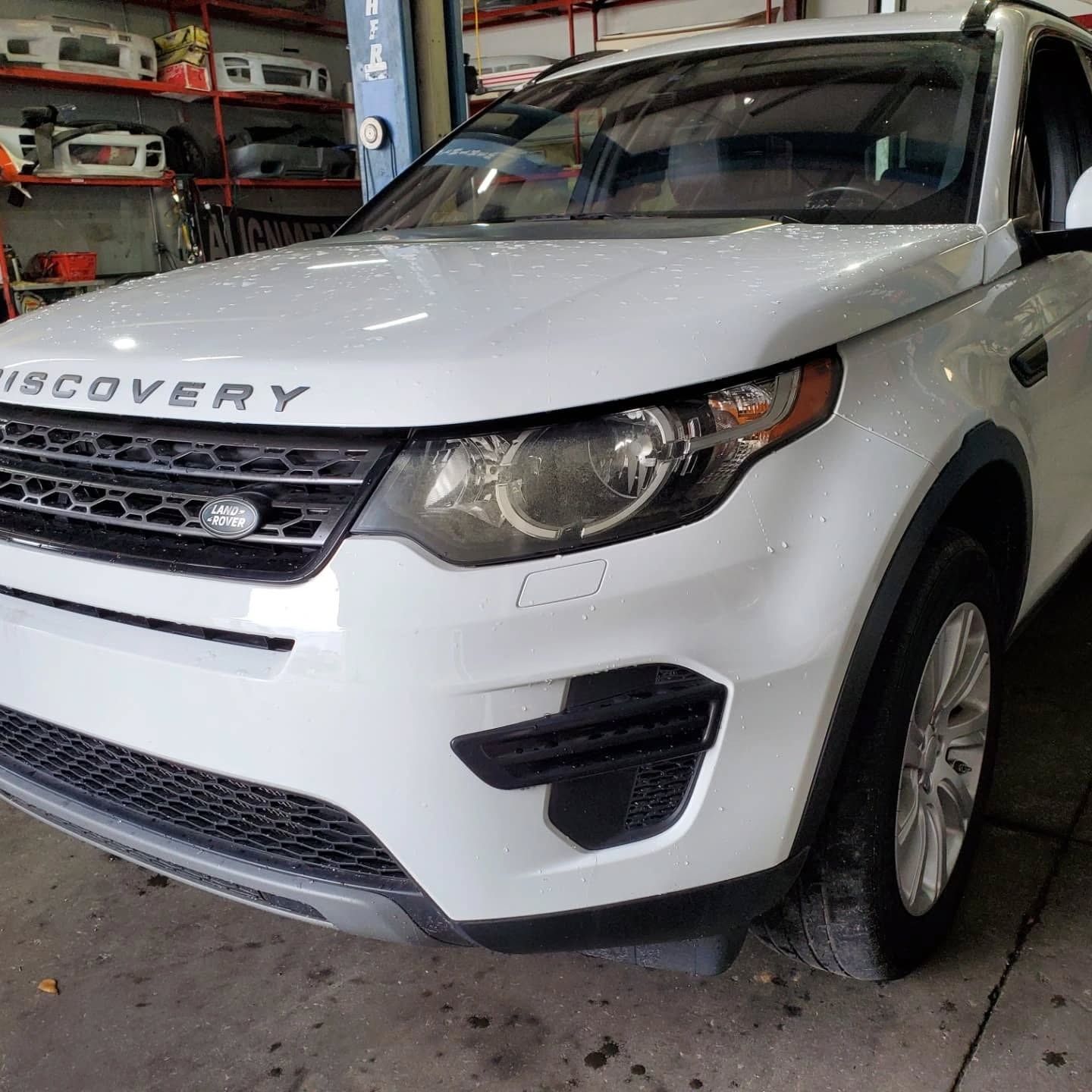 White Land Rover Discovery SUV parked inside a garage, front-left view