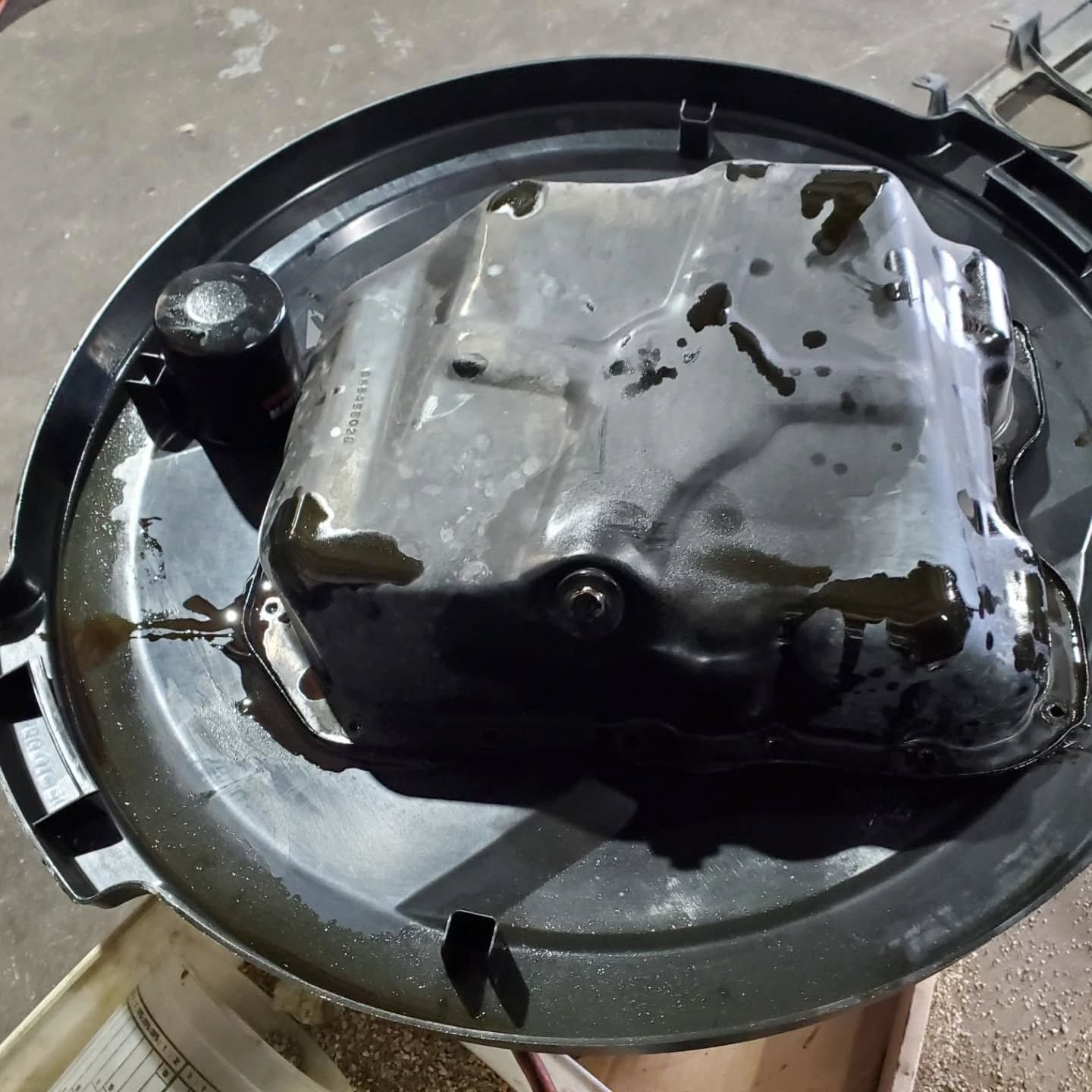 Blackened, crumpled metal object inside a round pan on a concrete floor