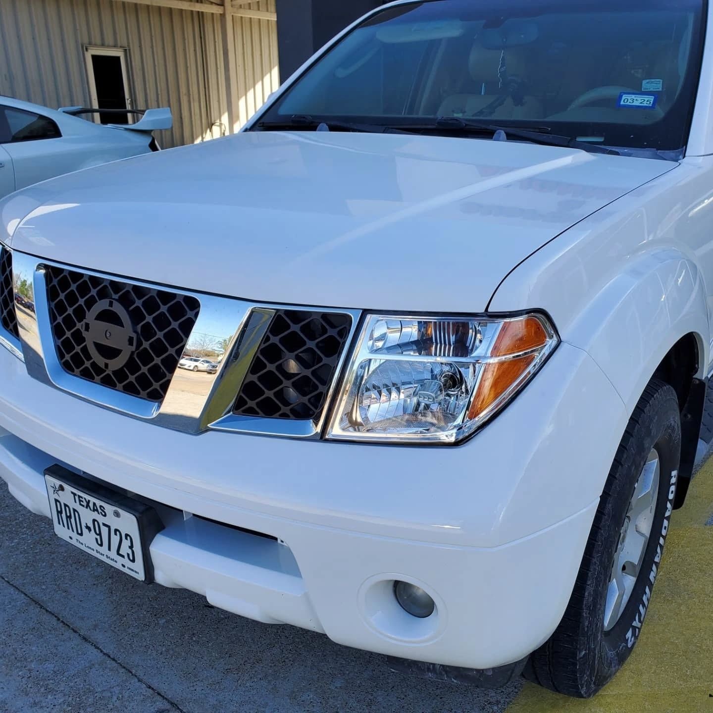 White Nissan SUV parked outdoors in front of a building