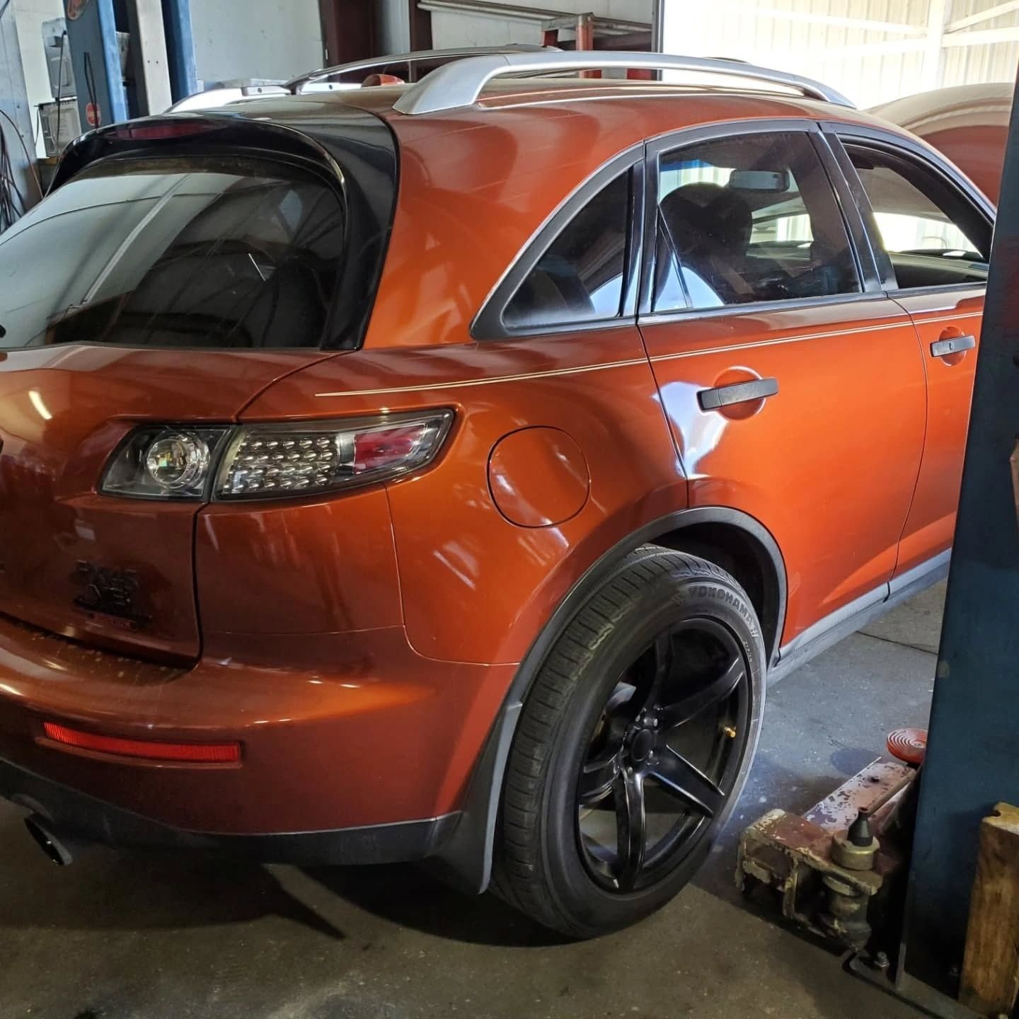 Orange SUV parked in a garage, viewed from the rear side.
