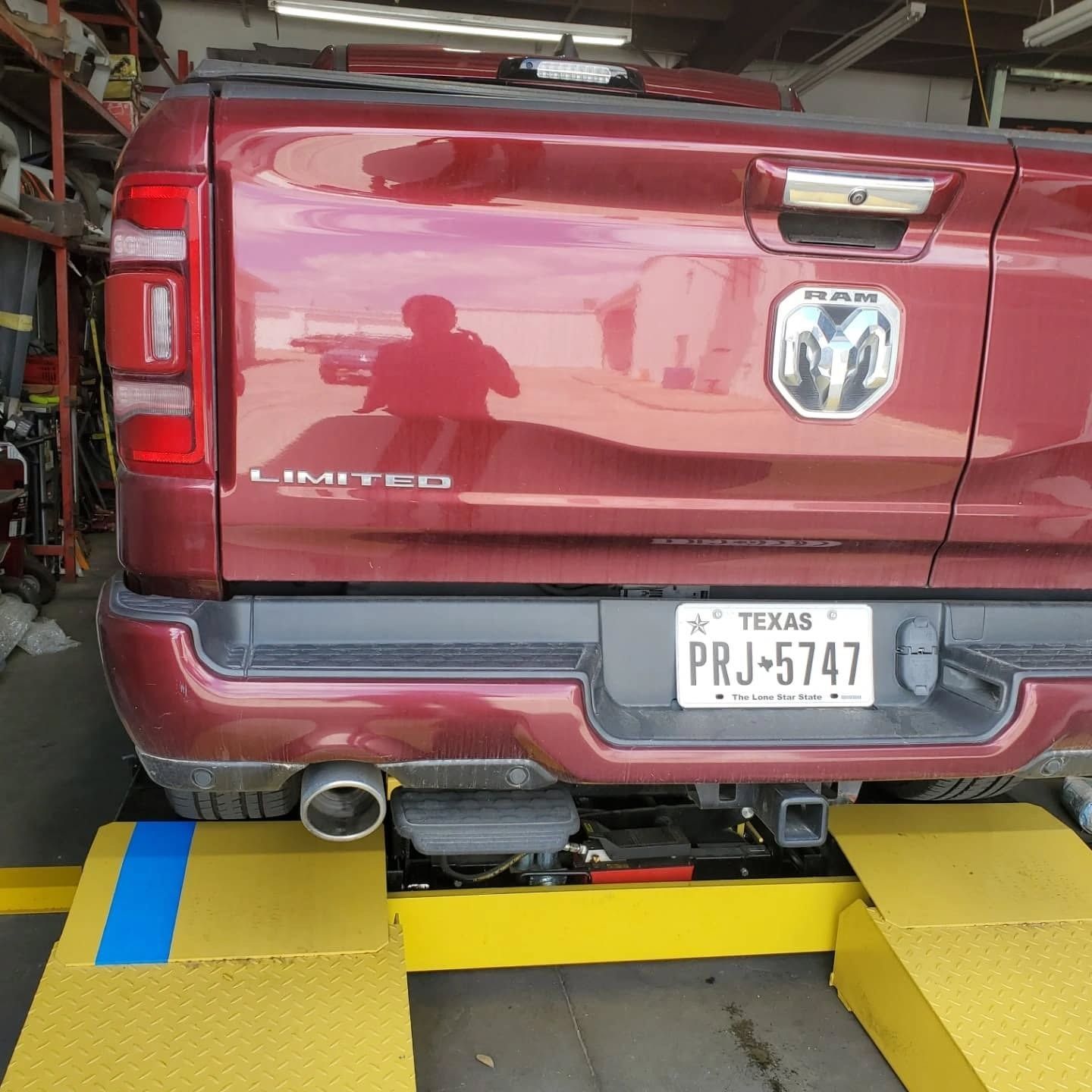 Maroon Dodge Ram pickup backed into a garage, rear view with Texas license plate and bumper visible