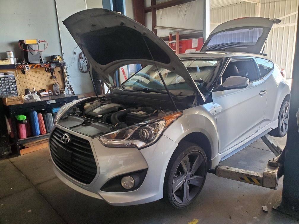 Silver SUV in a garage with hood open, showing the engine compartment on a service lift