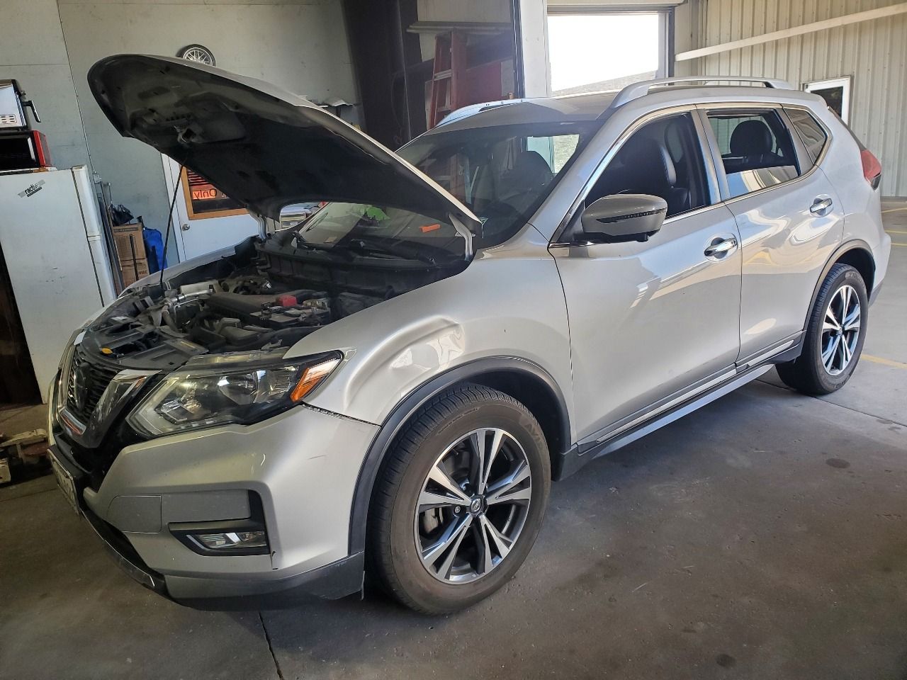Silver SUV in a garage with its hood open for inspection or repair