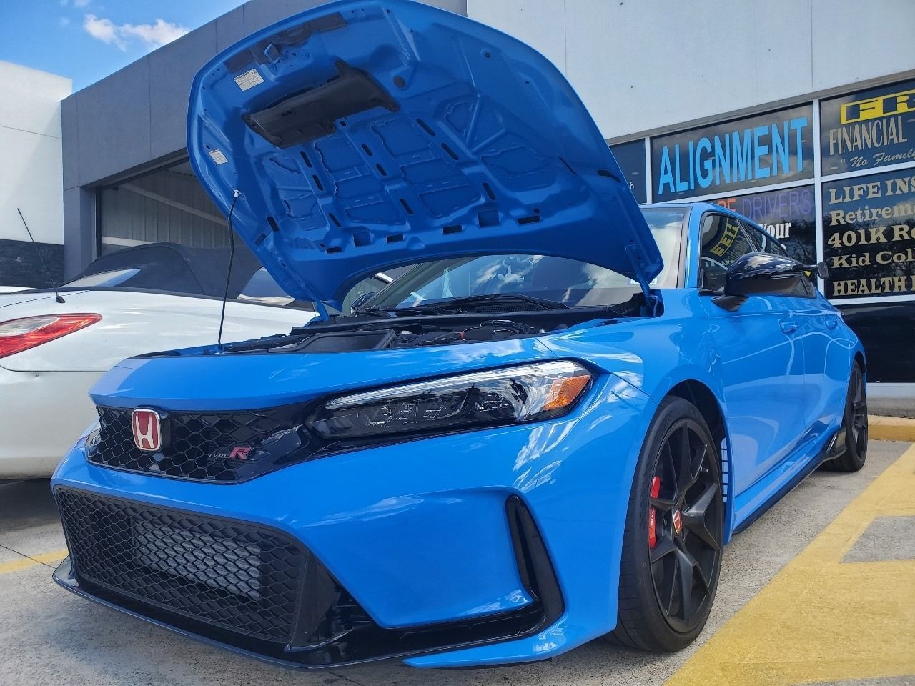 Blue Honda Civic with hood open in a parking lot, front view with black wheels and red calipers.