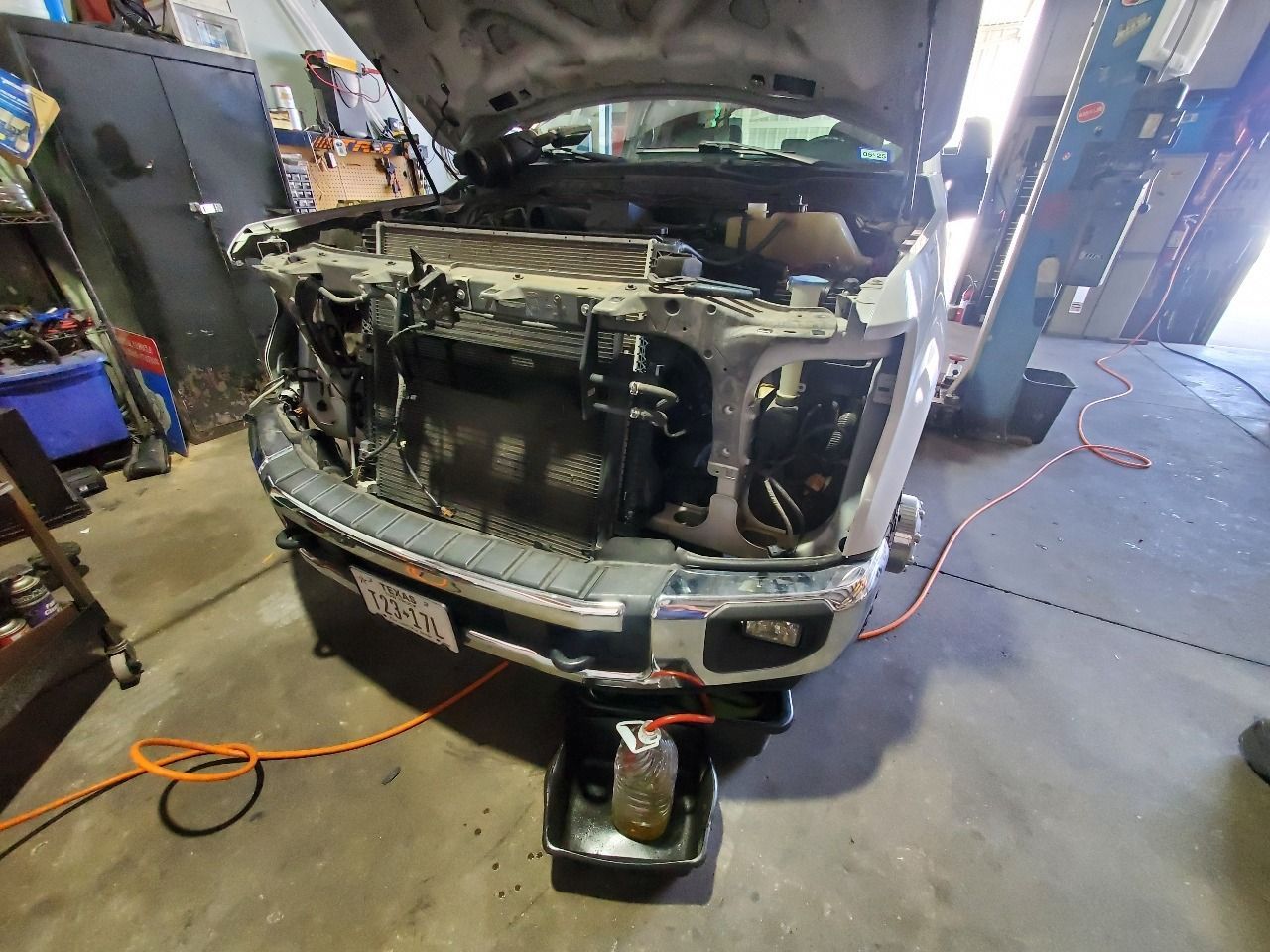 Truck in auto shop with front grille removed and hood open during repair