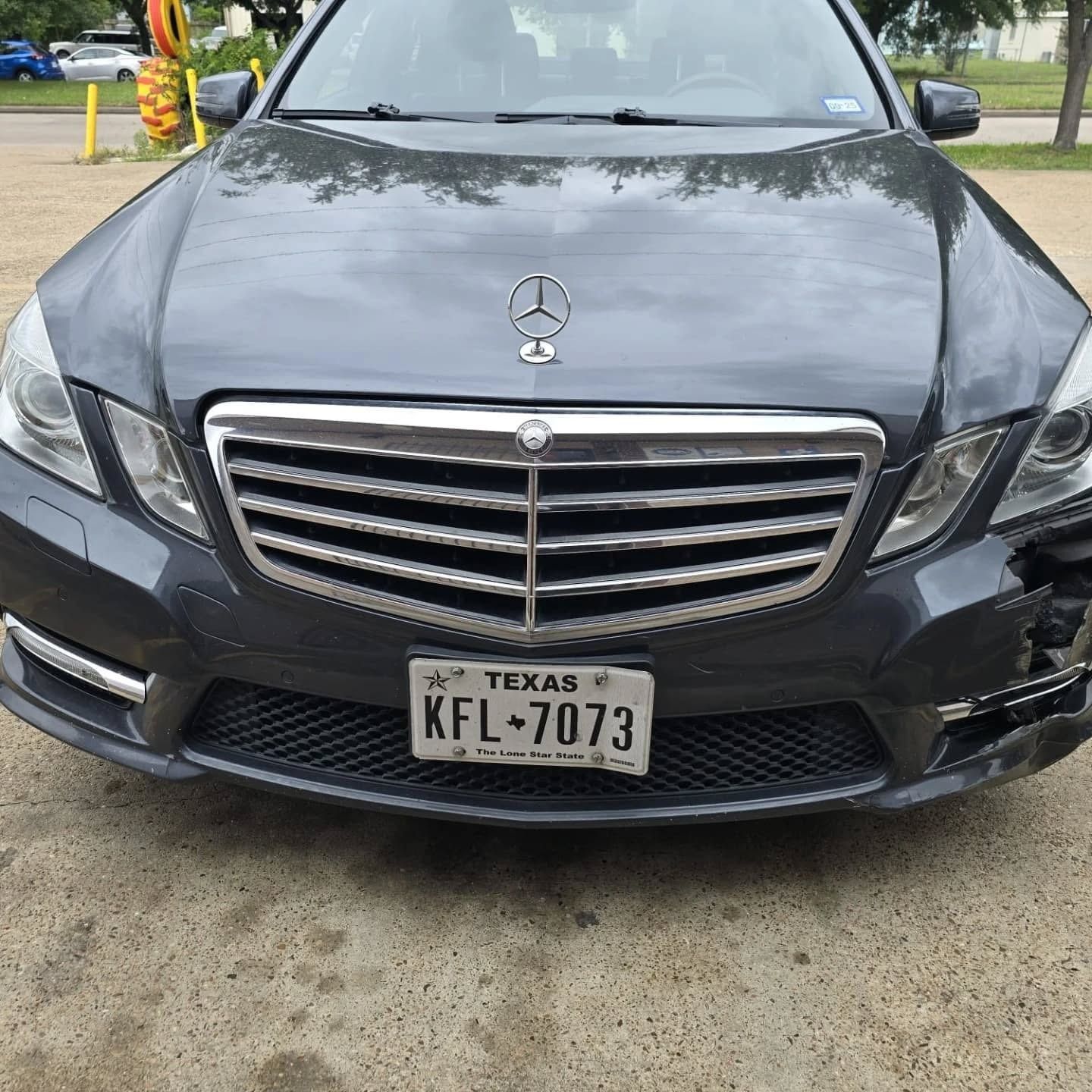 Front view of a black Mercedes-Benz sedan parked on pavement, with a visible license plate.