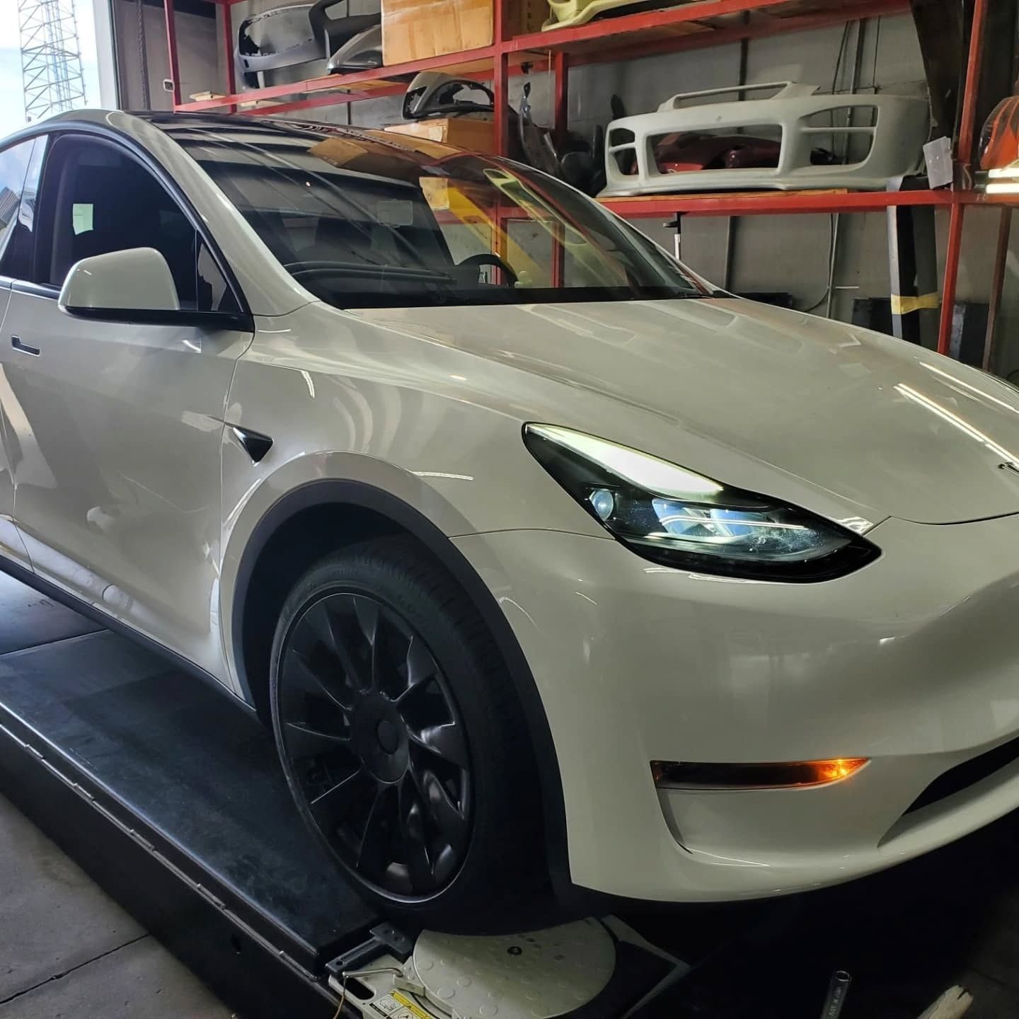 White electric SUV on a workshop lift inside an auto service garage