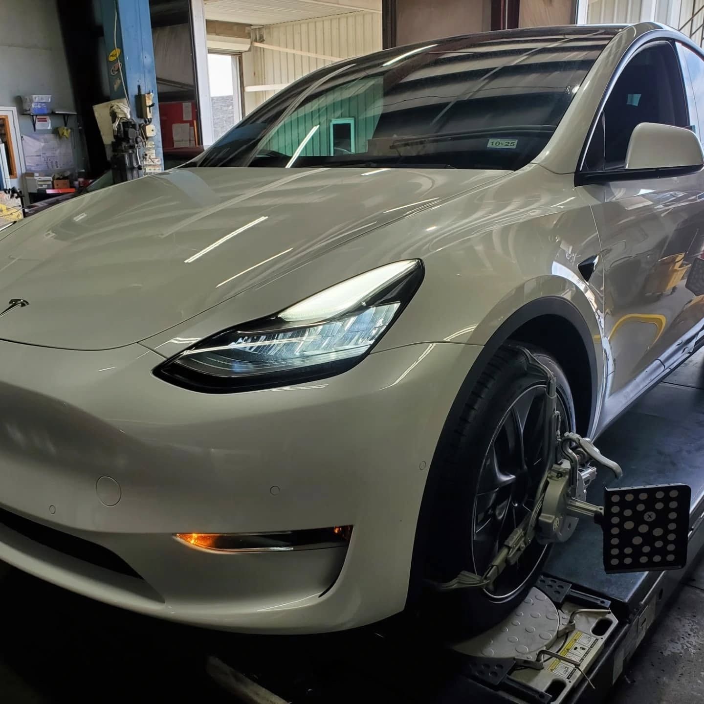 White Tesla SUV on a car lift inside an auto repair shop