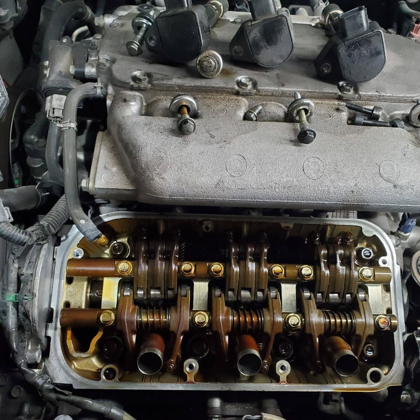 Close-up of an open car engine cylinder head with exposed camshaft and valve train.