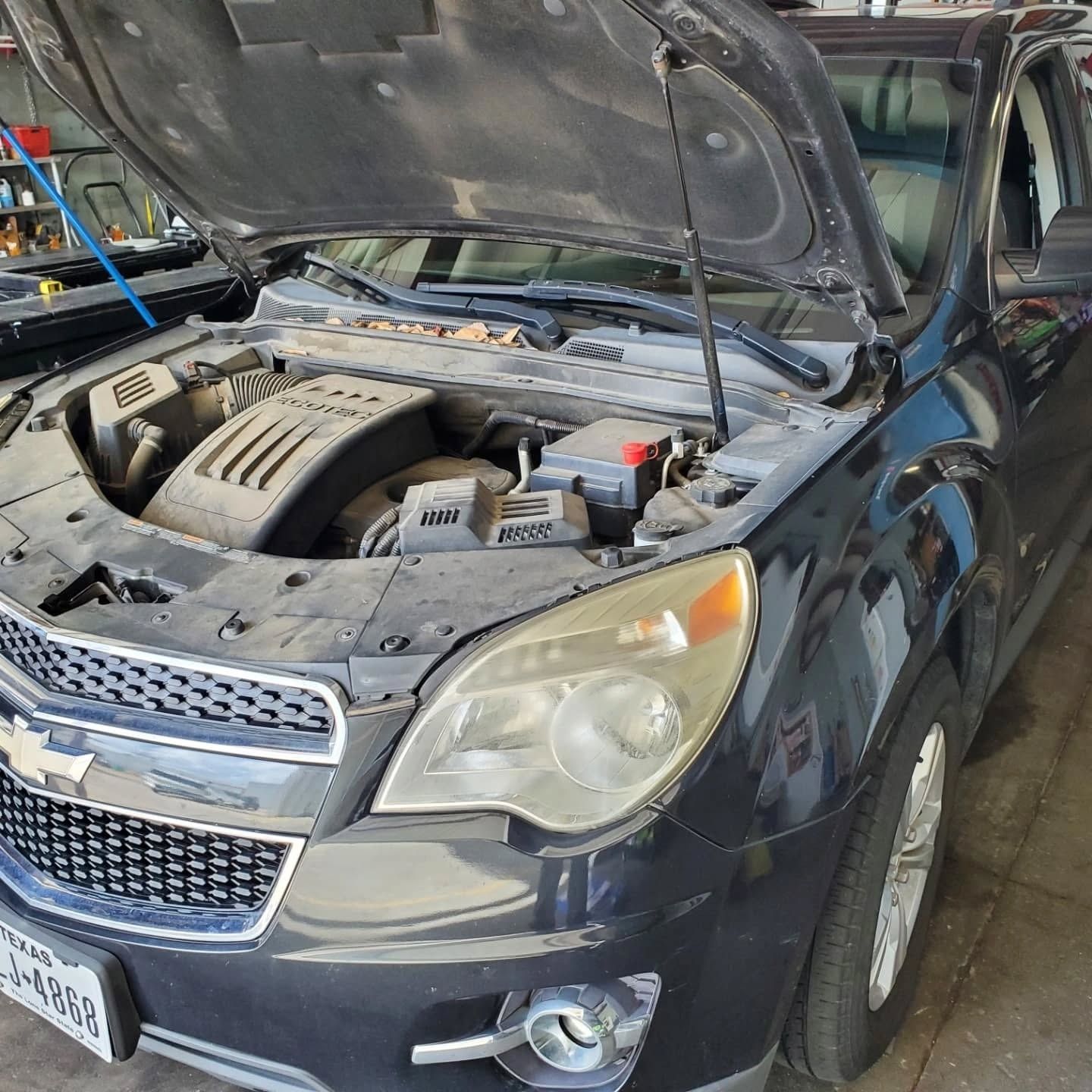 Black car with hood open in a garage, exposing the engine compartment