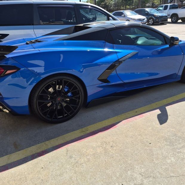 Blue sports car parked in a lot, side view with black wheels and dark tinted windows